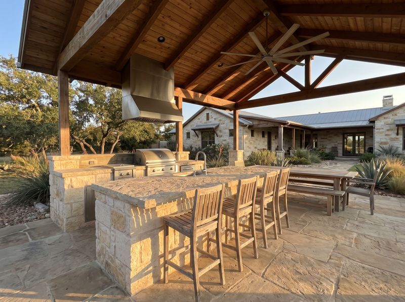 A covered outdoor kitchen with island seating at golden hour